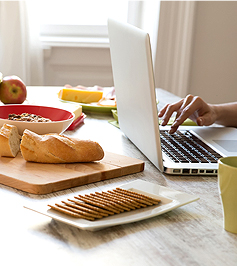 Eine Hand Tipps etwas auf eine Laptoptastatur ein und Frühstück steht auf dem massiven Holztisch