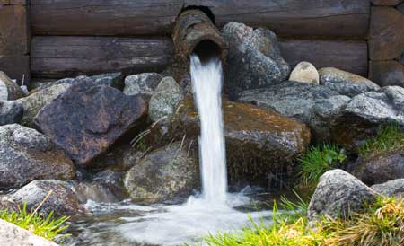 Ein plätschernder Brunnen aus Holz und Stein belebt den Bauerngarten