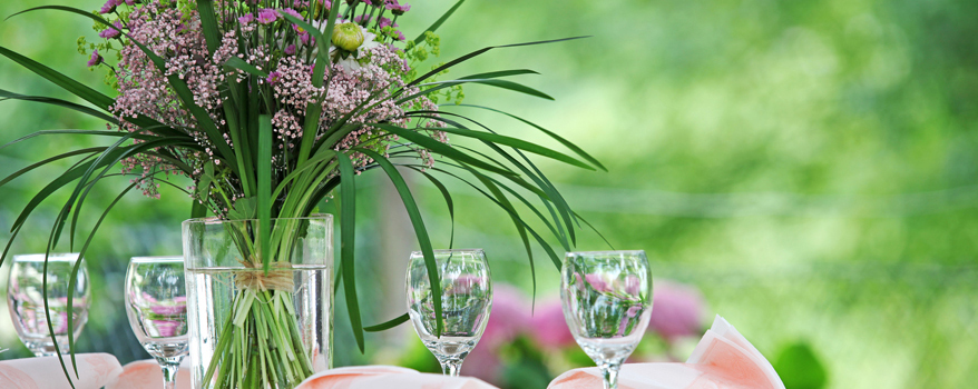 Ein selbstgemachtes Blumengesteck mit farbenfrohen, dekorativen Elementen für den Gartentisch