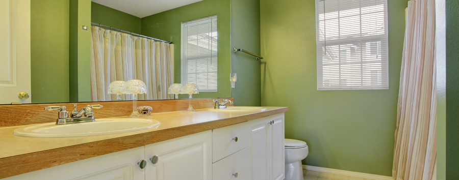 Grüne Wandfarbe im Bad strahlt Lebensfreude aus und passt zum Waschtisch aus hellem Holz